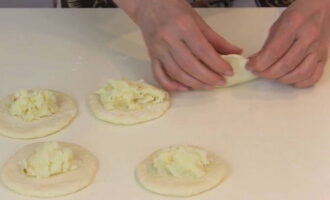 Ilagay ang naunang inihandang palaman sa gitna ng bawat flatbread gamit ang isang dessert na kutsara. Gagawin nitong mas madali para sa iyo na mag-navigate ayon sa volume. At kurutin ang cake sa paligid ng mga gilid, na bumubuo nito sa isang pie.