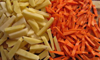 Schil, was en snij de resterende wortels. We doen hetzelfde met aardappelen en sturen ze naar de kokende bouillon. Voeg na 10 minuten wortels toe aan de aardappelen.