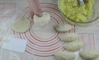 Împărțim aluatul crescut în bucăți egale și le rulăm în bile, pe care apoi le frământăm în prăjituri plate. Puneți umplutura în mijlocul fiecăruia și legați marginile.