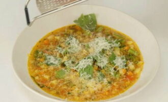 Eftersom vi behöver parmesan att servera, riv en bit på ett grovt rivjärn och låt stå i kylen tills den ska användas. Vi kontrollerar beredskapen för alla grönsaker och stänger av minestrone. Efter att ha stängt av, täck pannan med ett lock och låt soppan dra i ca 10 min. Tillsätt riven parmesan till varje portion soppa och servera.