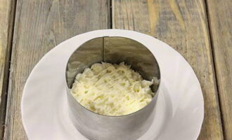 We beginnen de salade te vormen. Hiervoor kunt u een speciale ring gebruiken. Leg eerst het eiwit neer en giet er mayonaise overheen.