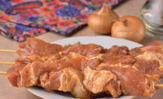 Mentre la carn de porc està saturada d'espècies, posem en remull els bastonets de fusta amb aigua perquè no es cremin al forn. Col·loqueu la polpa en vinagre directament sobre les broquetes humides.