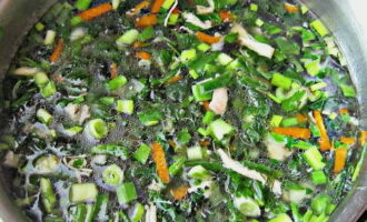 We hakken ook de groene uien en de greens en voegen ze toe aan de soep, waarna we deze ongeveer 10 minuten koken.
