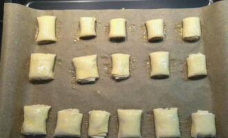Col·loqueu amb cura els trossos en una safata de forn, prèviament coberta amb un full de paper sulfuritzat per coure, i untem generosament amb l'ou batut restant.