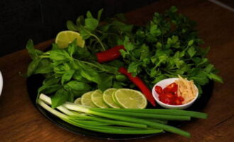 Vi förtvättar mynta, koriander och persilja, torkar dem och separerar bladen från stjälkarna. Skär lime i tunna skivor, chilipeppar i ringar och om så önskas kan du lägga till hackad ingefära.