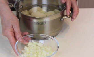 Balatan ang mga patatas, hugasan ng mabuti, gupitin sa ilang mga hiwa kung ninanais at ilagay sa isang kawali ng tubig. Sa turn, gupitin ang sibuyas sa mga cube at iprito sa langis ng gulay hanggang sa ginintuang kayumanggi.