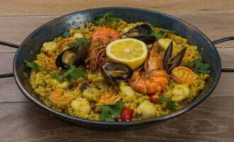 Serviți paella imediat în tigaie, ornata cu jumătate de lămâie și pătrunjel. Poftă bună!