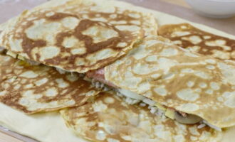 Bestrijk de bovenkant van de vulling met de overige pannenkoeken en snij de overhangende randen af.