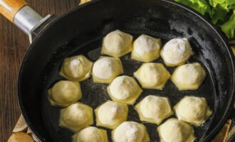Zet het snel op het vuur, giet de plantaardige olie erbij en verwarm het goed, zet het vuur laag en voeg de dumplings toe. Bak ze afgedekt ongeveer 4-5 minuten.