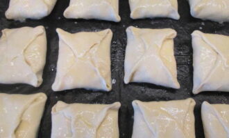 Pagulungin ang kuwarta sa mga sobre at isara nang mabuti ang mga gilid. Paghaluin ang yolk na may gatas at i-brush ang timpla sa mga piraso. Ilagay ang khachapuri sa isang baking sheet na pinahiran ng langis ng gulay.