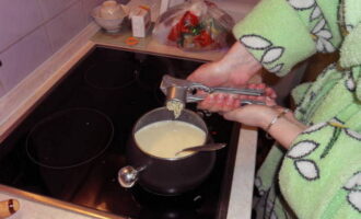 Se adauga apoi branza si se dizolva amestecand energic. După 5 minute, adăugați amidon, continuați gătitul, sosul trebuie să devină omogen și vâscos. Adăugați condimente și stoarceți usturoiul rămas printr-o presă.