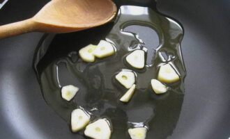 Gupitin ang bawang sa manipis na hiwa at bahagyang iprito sa isang kawali.