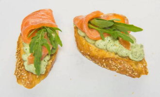 Peste amestec se aseaza felii de somon si se orneaza cu rucola. 