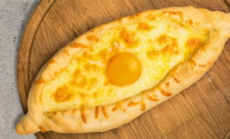Khachapuri finit se unge cu unt moale și se adaugă o altă bucată de unt la umplutura de brânză. Produsele de copt se lasă să stea pe masă sub un șervețel timp de aproximativ 5 minute și se servesc. Bucurați-vă!