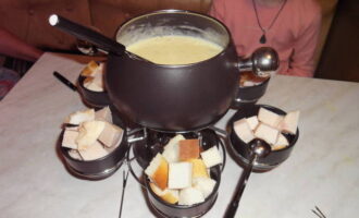 Puneți vasul pentru fondue pe arzător și serviți cu felii de pâine și carne.