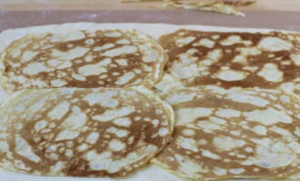 Rol het deeg uit op een werkblad en leg de pannenkoeken erop.
