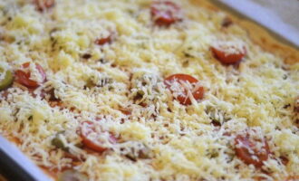Răziți brânza pe răzătoarea fină și presărați-o pe pizza. Stropiți puțin ulei de măsline deasupra pizza.