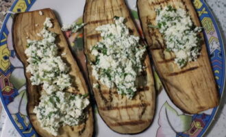 Lägg fyllningen på varje aubergineskiva och forma en rulle. De förberedda halvfabrikaten läggs tätt ihop i en ugnsform med sås, häll resten av marinaran ovanpå och strö över resten av mozzarellan och parmesanen. 