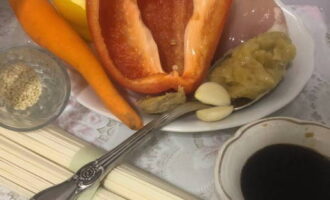 Cum să gătești tăiței udon cu pui și legume? In primul rand pregatiti toate ingredientele conform retetei. Curățați și clătiți legumele (piper, ghimbir și morcovi). Curățați cățeii de usturoi. Clătiți fileul de pui și uscați cu un șervețel.