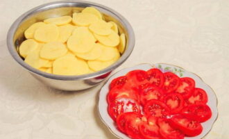 Gupitin ang mga patatas at kamatis sa manipis na hiwa.