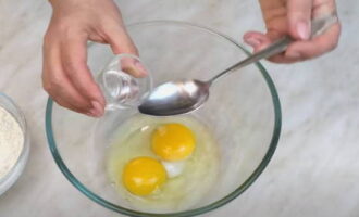 Hoe noedels thuis koken? Breek de eieren in een kom. Voeg zout en water toe, schud met een vork. Voeg de bloem in porties toe en kneed geleidelijk tot een dik, elastisch deeg. 