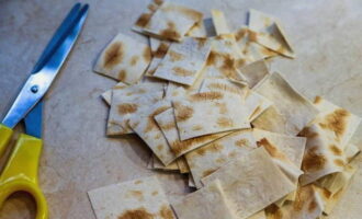 Hur gör man hemmagjorda pitabröd? Skär ett lager tunt lavash i små rutor. För att säkerställa att de kommer ut jämnt, använd en sax.