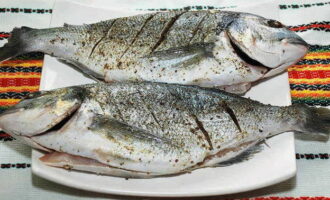 Vi gör grunda snitt (3-4 centimeter) på sidorna av fisken. Vi behandlar dorado inifrån och ut med en blandning av örter och kryddor.