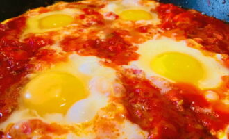 Facem șase depresiuni în matbukha (așa este numele masei de legume pe care tocmai am pregătit-o). Bateți ouăle și albușurile în trei dintre ele. Introduceți doar gălbenușurile în găurile rămase.