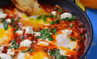 Stropiți shakshuka cu sare și piper. Asigurați-vă că albușurile devin albe și gălbenușurile rămân curgătoare. Spălați verdeața și tocați-le după cum doriți. Se presară peste shakshuka terminat. Serviți vasul pe farfurii preîncălzite. Daca pui vasul pe farfurii reci, se va desprinde si nu va fi la fel de gustos.