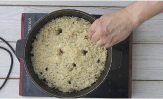 Tik na 10 minuten met een schuimspaan op de wand van de ketel en als het geluid dof is, maak dan lekke banden in de pilaf met een stok op de bodem van de ketel om de stoom erdoorheen te verwijderen.