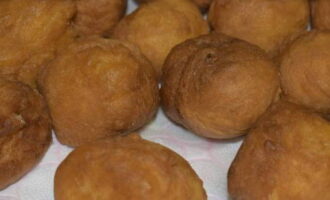 Verwijder de gebruinde donuts met een schuimspaan en plaats ze op een bord dat vooraf is bekleed met keukenpapier om overtollige olie te verwijderen.