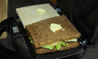 Ilagay ang mga sandwich sa isang multi-baker at ilagay ang isang maliit na piraso ng mantikilya sa ibabaw ng bawat sandwich para sa isang creamy lasa.