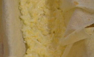 Inilalagay namin ang baking dish na may lavash upang ang mga gilid ay nakabitin - sagana na pinahiran ng tinunaw na mantikilya, at inilalagay ang bahagi ng pagpuno ng keso sa gitna at pakinisin ito. 
