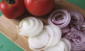 Twee soorten gepelde uien worden in dunne halve ringen of ringen gesneden, tomaten - in blokjes.