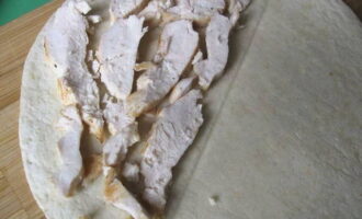 Leg het bereide kippenvlees in elke tortilla, strooi er kaas over en verdeel de plakjes peper. 