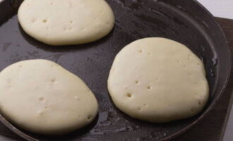 Doe het deeg met een in water gedoopte eetlepel in een verwarmde koekenpan en bak de pannenkoeken op matig vuur aan beide kanten.