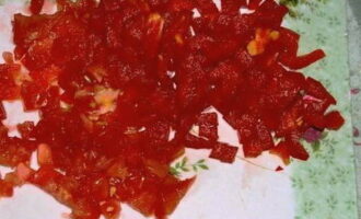 We wassen de tomaat, drogen hem, snijden hem in stukjes en snijden de zaden en het sap eruit. Snijd het resterende vruchtvlees in blokjes. We maken de paprika schoon van scheidingswanden en zaden en hakken hem op dezelfde manier fijn.