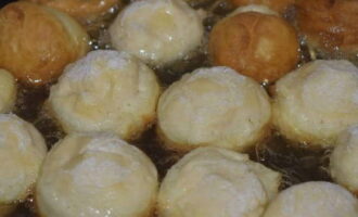 Verhit in een koekenpan met hoge zijkanten bijna een heel glas plantaardige olie en leg de donuts voorzichtig neer.