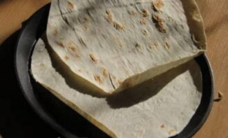 Com cuinar una pizza de pita mandrosa en 10 minuts en una paella? Del pa de pita retallem dos cercles que s'ajustin a la paella.