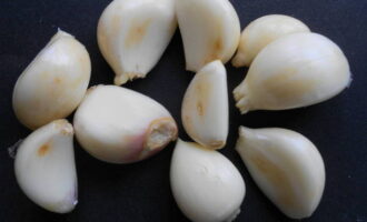 Neem een ​​bol knoflook en verdeel deze in teentjes. Vervolgens bevrijden we elk kruidnagel van de schil en spoelen we af onder stromend water. Leg de helft van de kruidnagels op een bord: we hebben ze nodig bij het vullen van de vogel.