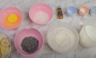 Într-un castron, amestecați ingredientele uscate: făina, sarea, bicarbonatul de sodiu și praful de copt. Separat, batem ouăle cu zahărul până devin spumă, apoi turnăm laptele și extractul de vanilie. Amestecați treptat amestecul uscat și amestecul lichid de ou-lapte, adăugați piure de banane și frământați într-un aluat omogen. La sfârșit, adăugați fulgii de ciocolată. 