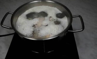 Vul alles met water, zet het op het vuur en breng aan de kook. Kook gedurende drie minuten, giet vervolgens de bouillon af, spoel het vlees opnieuw goed af en doe het in een schone pan.