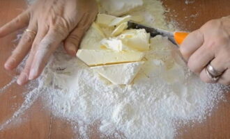 Làm thế nào để nướng một chiếc bánh hành cổ điển tại nhà? Rây lượng bột mì cần thiết lên bề mặt làm việc của bàn. Thêm bơ lạnh vào và dùng dao cắt nhỏ cho đến khi trở thành những mảnh vụn mịn.
