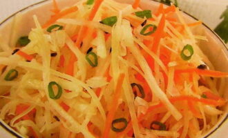 We kiezen een mooie slakom van een geschikt formaat en doen er geraspte wortelen, radijsjes en gehakte groene uien in. Meng de salade grondig en voeg zout naar smaak toe.