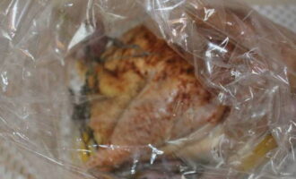 วางไก่ไว้ในซองสำหรับอบ เรายังส่งกระเทียมพร้อมมะนาวและโหระพาที่นี่ด้วย