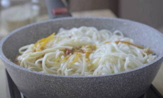 Kook de udon-noedels apart en voeg ze toe aan het gerecht. Roer voorzichtig en haal van het vuur. Voeg groene uien en sesamzaadjes toe.