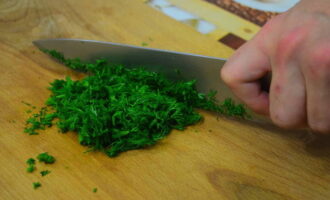 We wassen de greens die je aan het khachapuri-deeg wilt toevoegen. We verwijderen overtollig vocht door de bundel te schudden. Snijd het ingrediënt fijn en voeg het toe aan het deeg.