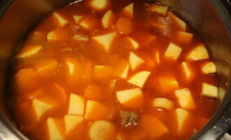 Torneu a bullir la barreja i deixeu-ho coure a foc lent durant aproximadament mitja hora. Si les patates encara no s'han cuinat i es tornen toves, continueu la cocció. A continuació, apagueu el foc i afegiu-hi julivert, prèviament rentat i picat, al plat. Tapeu la paella amb una tapa, deixeu que la barreja espessi i s'inclou.