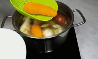 Haal na een half uur de wortels uit de bouillon en doe ze op een bord. Voeg 30 minuten voor het koken van de kip laurier en zout naar smaak toe aan de bouillon. 