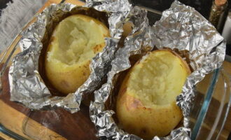 Nadat de aardappelen bruin zijn geworden, haalt u ze uit de oven. Laat het product afkoelen. We verwijderen de schil van het oppervlak van de aardappelen en gebruiken een vork of lepel om het vruchtvlees te verwijderen (er moet een kleine uitsparing ontstaan ​​voor de vulling). 